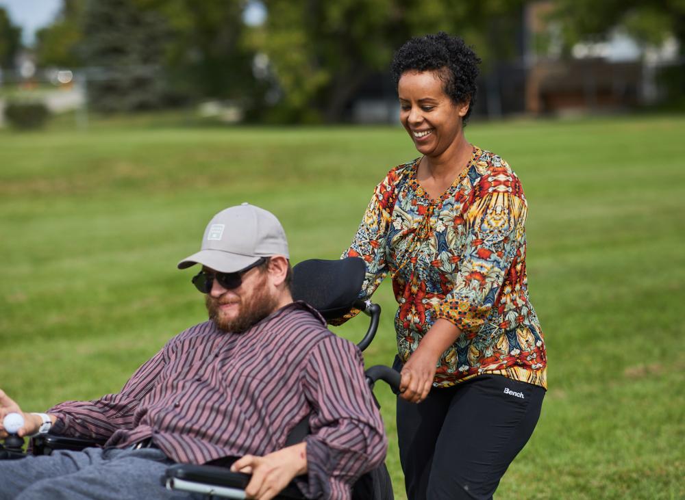 woman pushing man in wheelchair outside