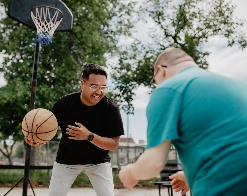 Two people playing basketball outside